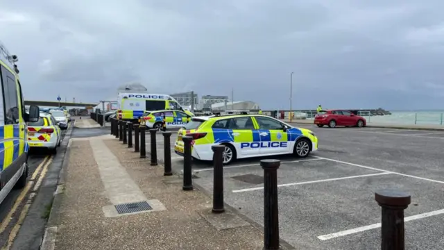 A number of police vehicles are parked close to the seafront