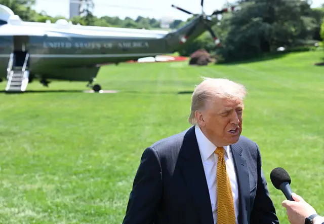 Trump speaks on the White House lawn with a helicopter in the background