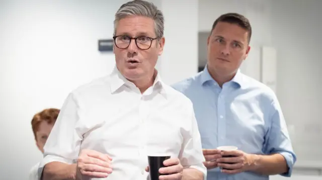 Streeting and Starmer pictured in September 2024, they are both wearing shirts with the sleeves rolled up and holding cups of coffee
