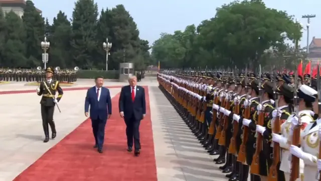 Trump and Xi walking donw a red carpet as troops stand in neat rows to their side