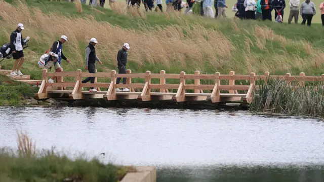 Scottie Scheffler and Matt Fitzpatrick walk across a bridge