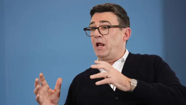 Andy Burnham in front of a blue background