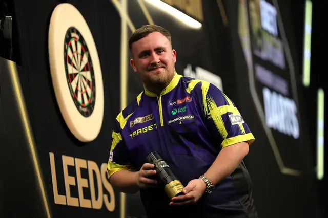 Luke Littler holding Premier League night 14 trophy