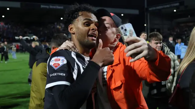 Jacon Bedeau of Notts County is kissed by a fan while taking a selfie