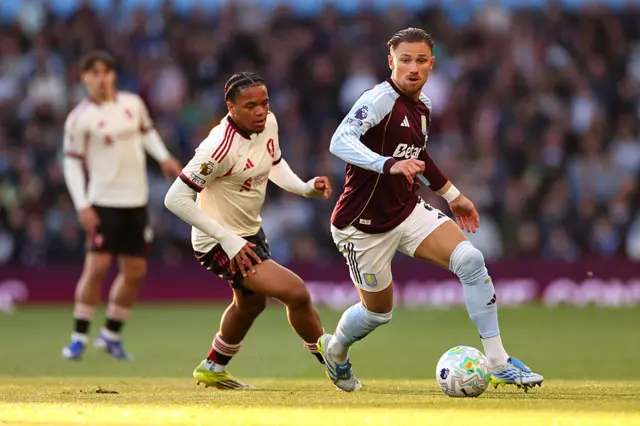 Matty Cash of Aston Villa runs with the ball while under pressure from Rio Ngumoha