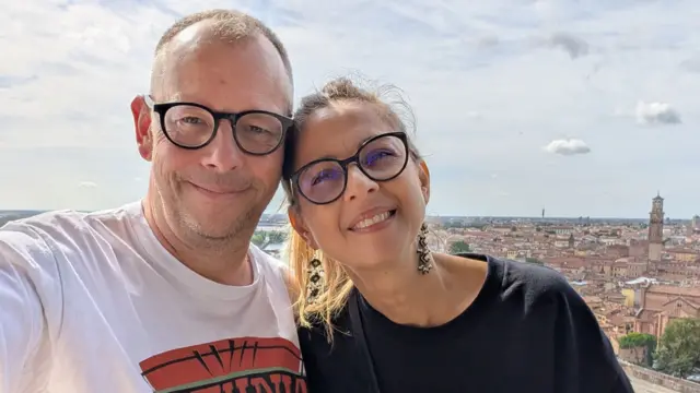 Scott and Andreea smiling taking a selfie in front of a view over the top of a historic old city