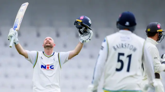 Yorkshire batsman Adam Lyth looks skywards with his bat raised in his right hand and his helmet raised in his left after scoring a century against Surrey.