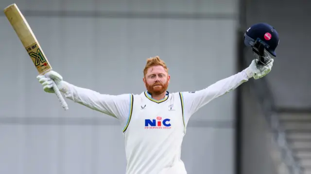 Yorkshire batsman Jonny Bairstow holding his bat in his right hand and helmet in his left hand in celebration after scoring a century against Surrey.