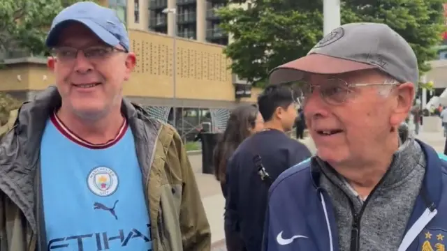 Gary and Phil wearing Manchester City tops outside Wembley stadium