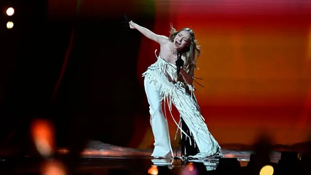 Woman in white costume sings on stage