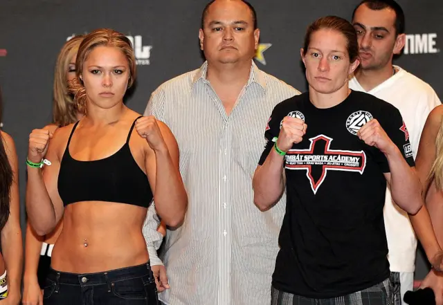 Ronda Rousey and Sarah D'Alelio hold up their fists as Scott Coker stands in the background