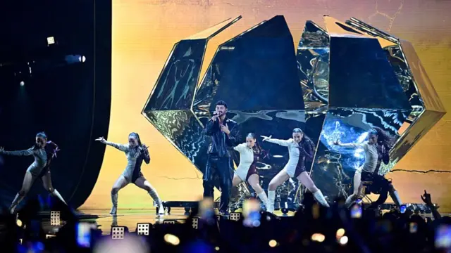 Bettan in front of a huge diamond and dancers as he sings