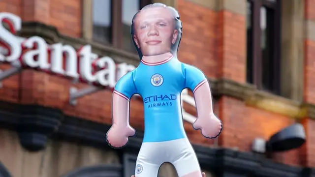 A fan holds up an inflatable doll with the face of Manchester City's Erling Haaland