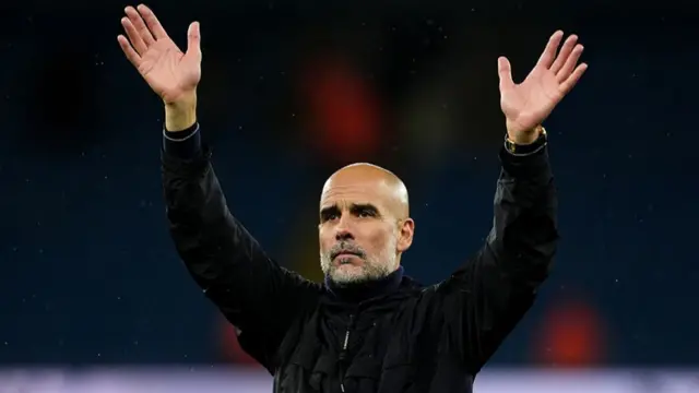Manchester City manager Pep Guardiola with a black top on raising his hands in the air