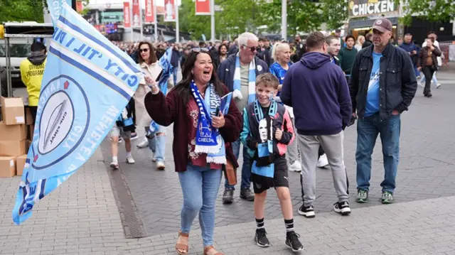 Manchester City fans including a woman with a young boy on Wembley Way