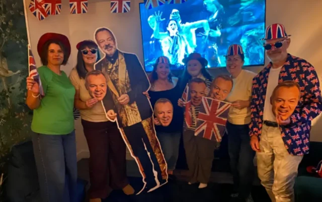 Five people stood holding Graham Norton cardboard cutouts wearing Union Jacks and standing in front of the TV