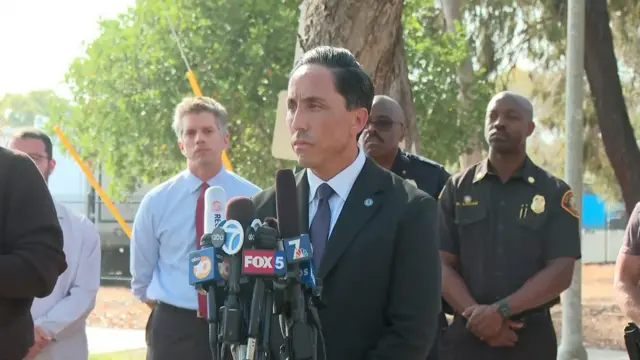 Mayor in dark suit stands behind microphone