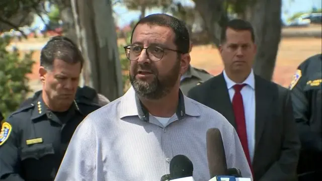 The imam speaks with police behind him