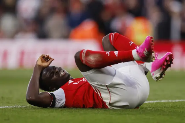 Saka holds his leg while lying on the floor