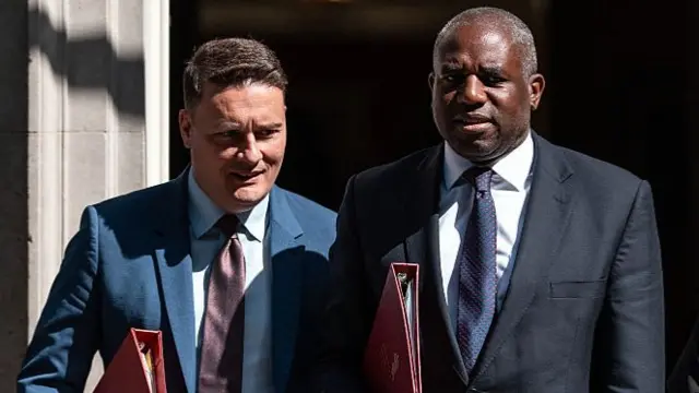 David Lammy and Wes Streeting walk together out of No 10 Downing Street carrying their red government folders on a sunny day in London