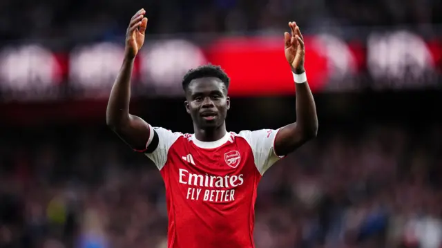 Saka throws his arms in the air