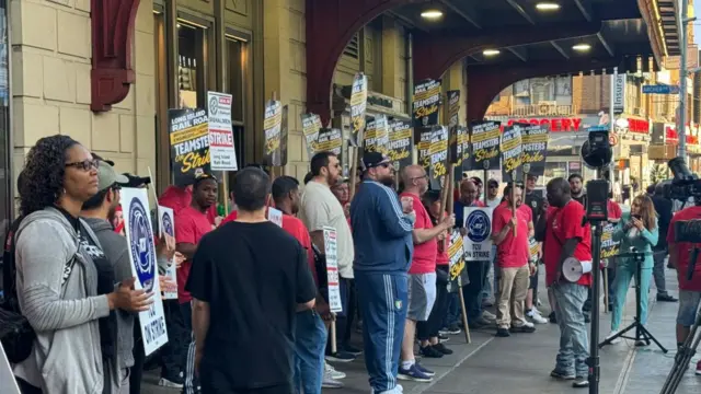 A crowd of picketers hold signs outside a train station during a strike