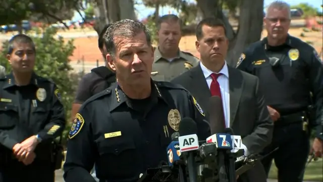 The police chief speaking with other officials in the background