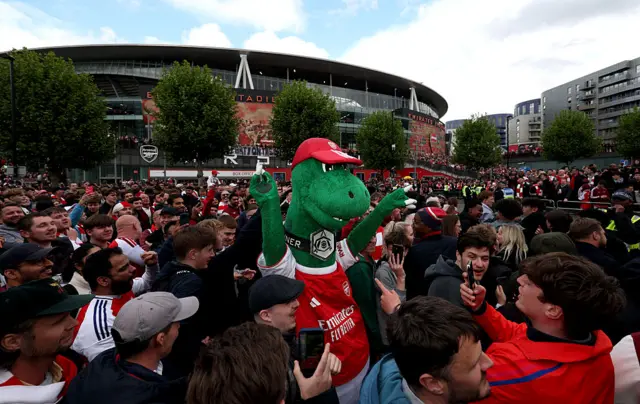 Gunnersaurus, Mascot of Arsenal, enjoys the pre match atmosphere with fans outside the stadium