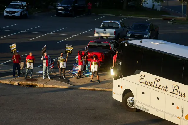 Long Island Rail Road workers picket as a shuttle bus leaves the Huntington, New York, LIRR station