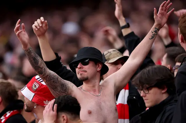 Shirtless fan waves his arms in the stands