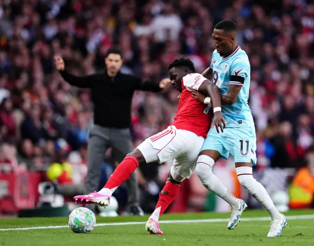 Saka holds off a defender