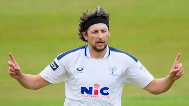 Yorkshire's Jack White celebrating taking a wicket with his arms out wide and index fingers raised.