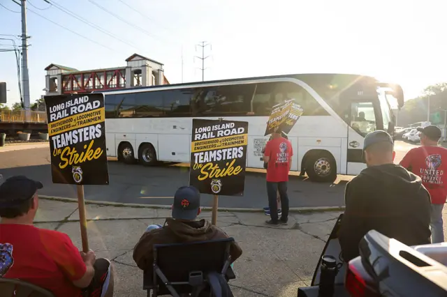 Long Island Rail Road workers picket as a shuttle bus leaves the Huntington, New York, LIRR station