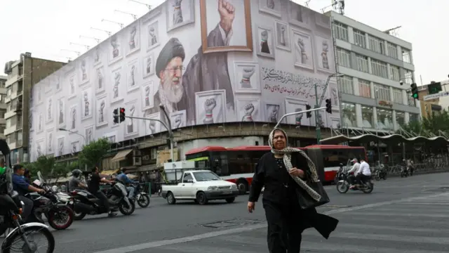 A woman walks near a billboard with an image of the late Iranian Supreme Leader Ayatollah Ali Khamenei, in Tehran
