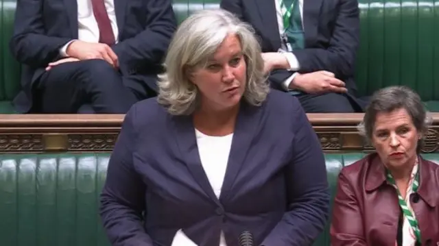 Transport Secretary Heidi Alexander standing at the dispatch box in a dark blue blazer and white top, colleagues sitting on the green leather benches of the Commons