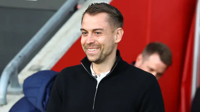 Tonda Eckert, wearing a black fleece, smiles while on the touchline during Southampton's game against Ipswich