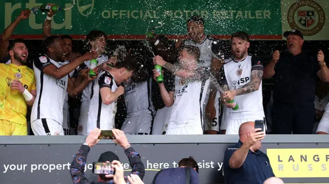 Bromley players spraying champagne to celebrate winning the League Two title