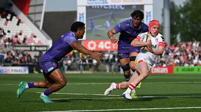 Michael Lowry (right) runs towards the line with the ball under his right arm as Immanuel Feyi-Waboso (left) runs towards him and another Exeter player runs behind