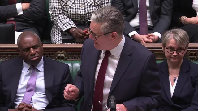 Starmer looks to his side as he speaks during PMQs. David Lammy and Yvette Cooper flank him on the front bench.