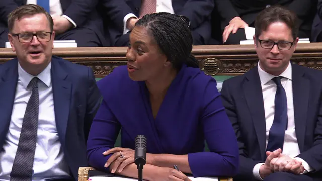 Kemi Badenoch looks to her side as she speaks during PMQs. She is wearing a purple top.