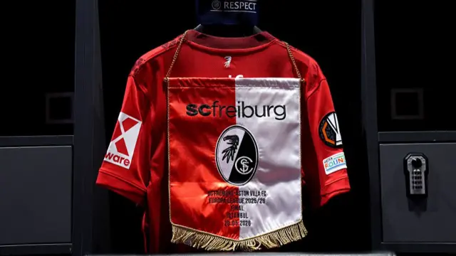 : A detailed view of the match pennant with the details 'SC Freiburg v Aston Villa, Europa League Final 2026, Besiktas Park, 20 May 2026' embroidered, seen inside the Sport-Club Freiburg dressing room