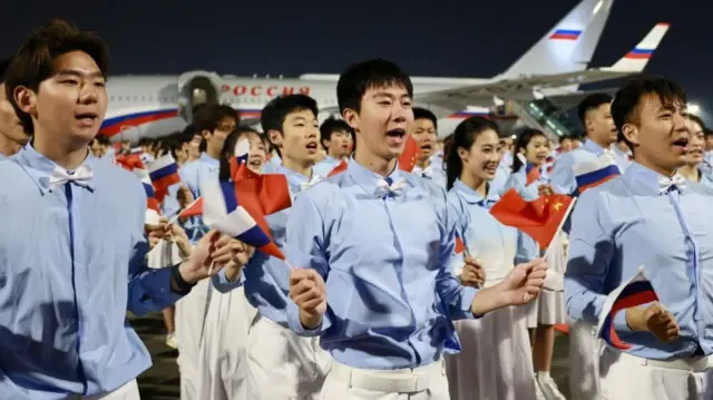 Chinese people with Russian flags greet Russian President Vladimir Putin after his arrival at the airport