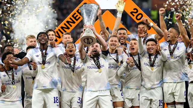 John McGinn of Aston Villa lifts the UEFA Europa League trophy with teammates