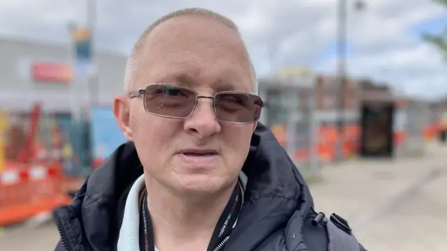 A man wearing glasses and a blue coat with a backpack on.
