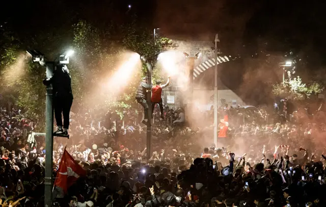 Fans hang off lampposts