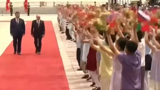 Children cheer as they greet Putin and Xi on red carpet