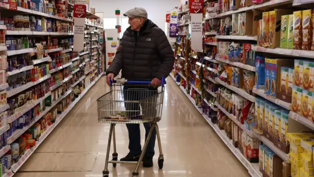 A man pushes a trolley in a supermarket aisle