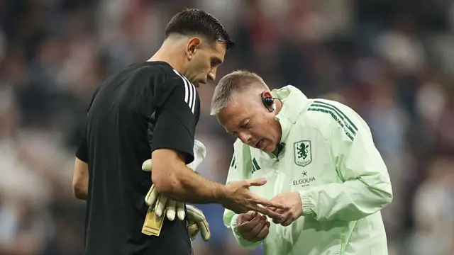 Emiliano Martinez of Aston Villa has his hand check by a member of Aston Villa staff