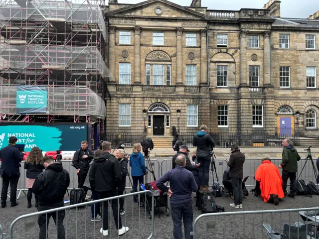 A group of media workers with cameras in the streets outside Bute House