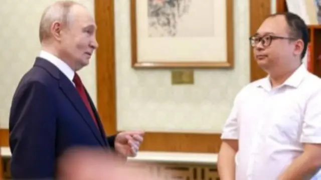 Putin speaking to a Chinese man wearing black spectacles